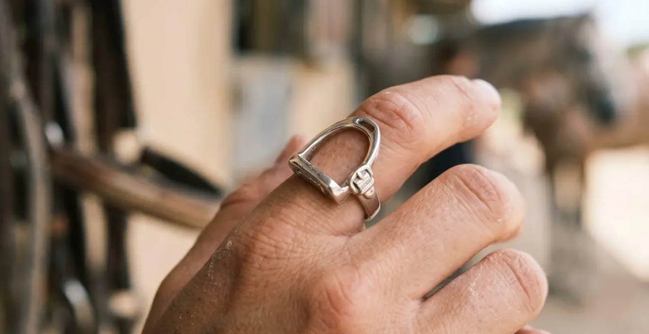 Gros plan d'une bague en argent rhodié étincelante portée par une cavalière, capturant l'éclat blanc argenté du métal sur un fond minimaliste