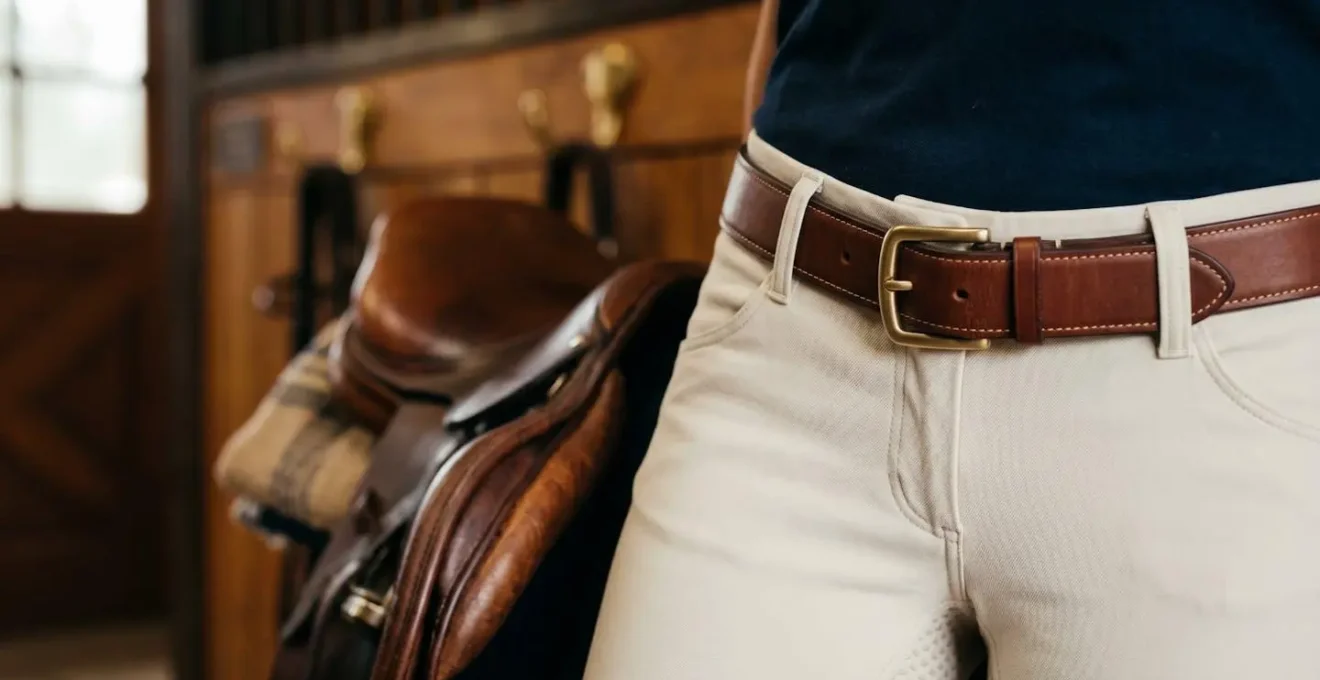 Détail d'une ceinture d'équitation élégante sur un pantalon technique près d'une selle
