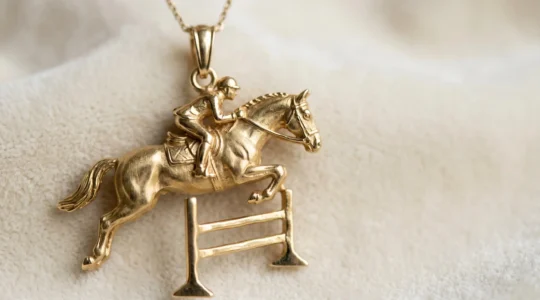 Détail macro d'un pendentif en or représentant un cheval au planer au-dessus d'un oxer, capturant la bascule et l'extension des antérieurs avec un réalisme sculptural