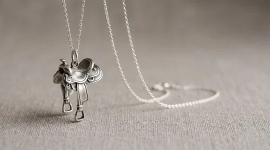 Pendentif selle équestre en argent massif suspendu à une chaîne forçat sur fond minimaliste